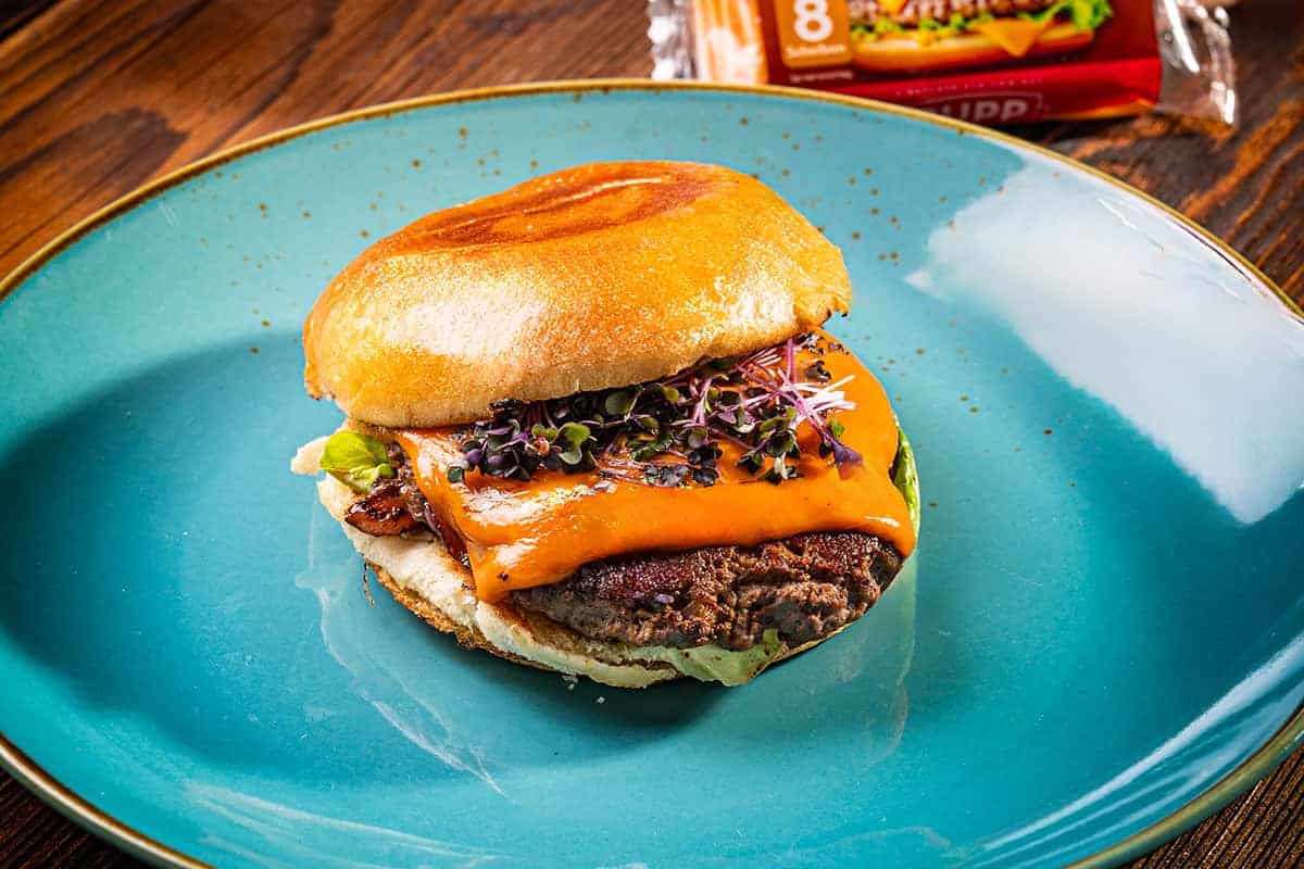 Smash Burger mit roten Zwiebeln und Adis Grillsauce auf blauem Teller