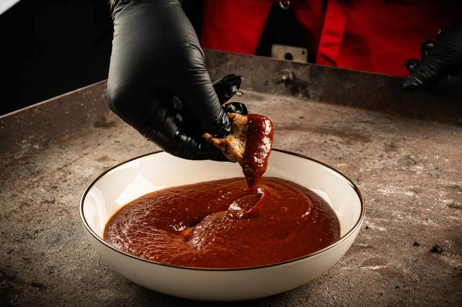 Hühnerbrust wird in dunkelrote BBQ-Sauce getunkt