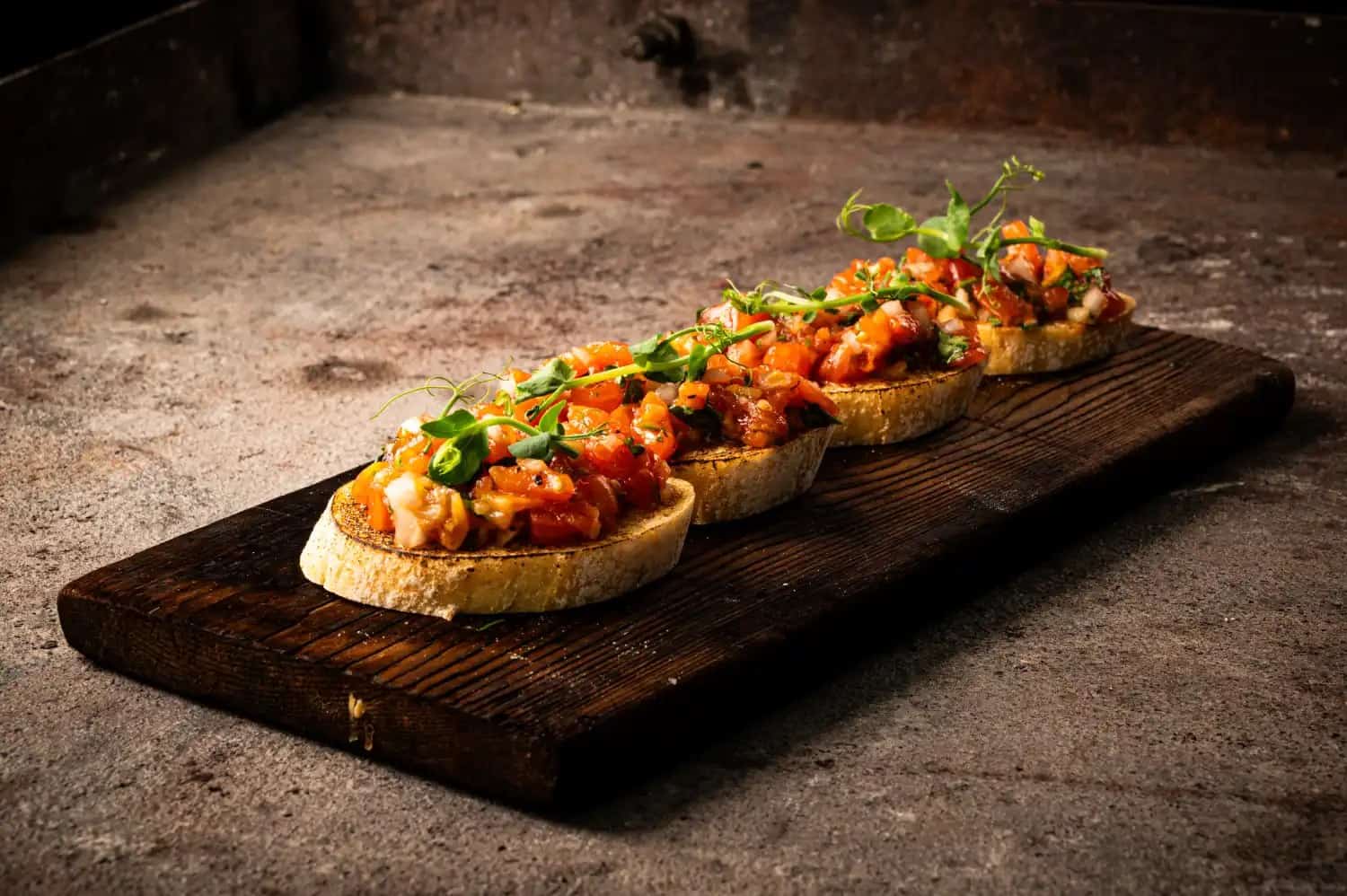Geröstete Brotscheiben mit gegrillter Tomaten-Salsa und Kräutern auf Holzbrett