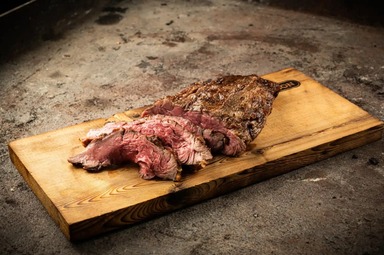 In Joghurt-Marinade gegrilltes, aufgeschnittenes Fleisch auf Holzbrett