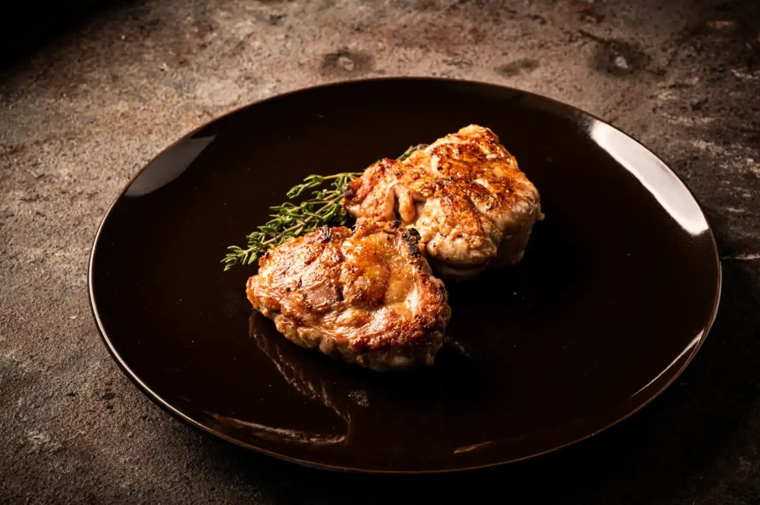 Gegrilltes Kalbsbries mit goldbrauner Kruste auf braunem Teller