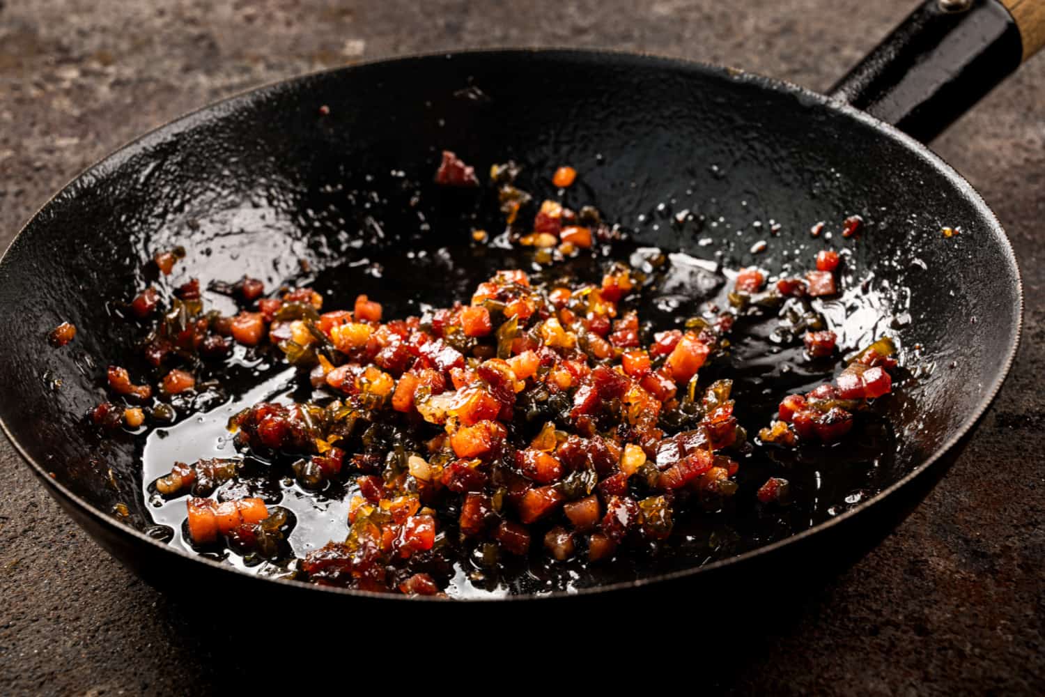 Chili Bacon Jam mit Speckwürfeln und Peperoni in einer gusseisernen Pfanne
