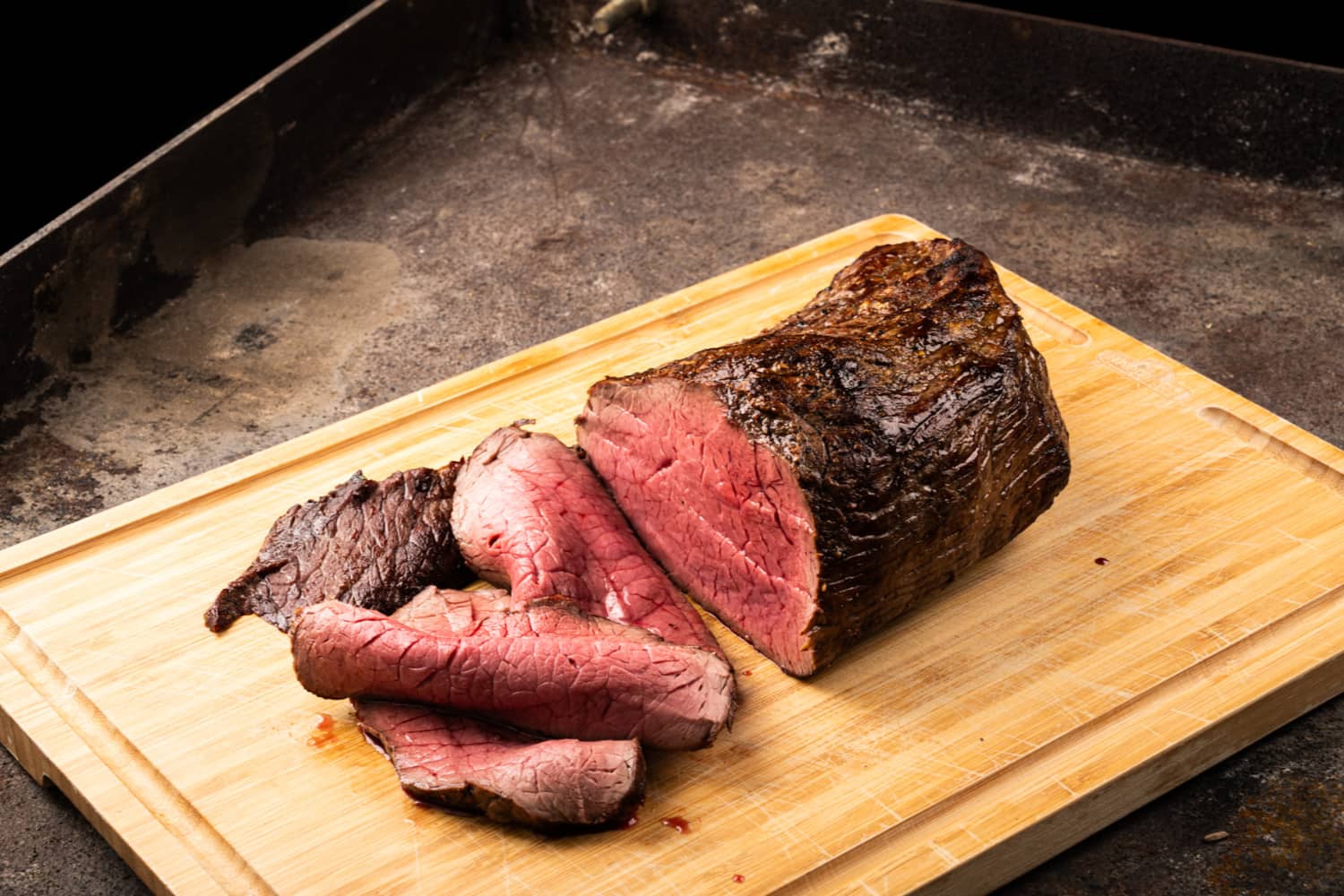 Aufgeschnittenes Tomahawk Steak vom Ötscherblick Schwein auf Holzbrett, rosa gegrillt